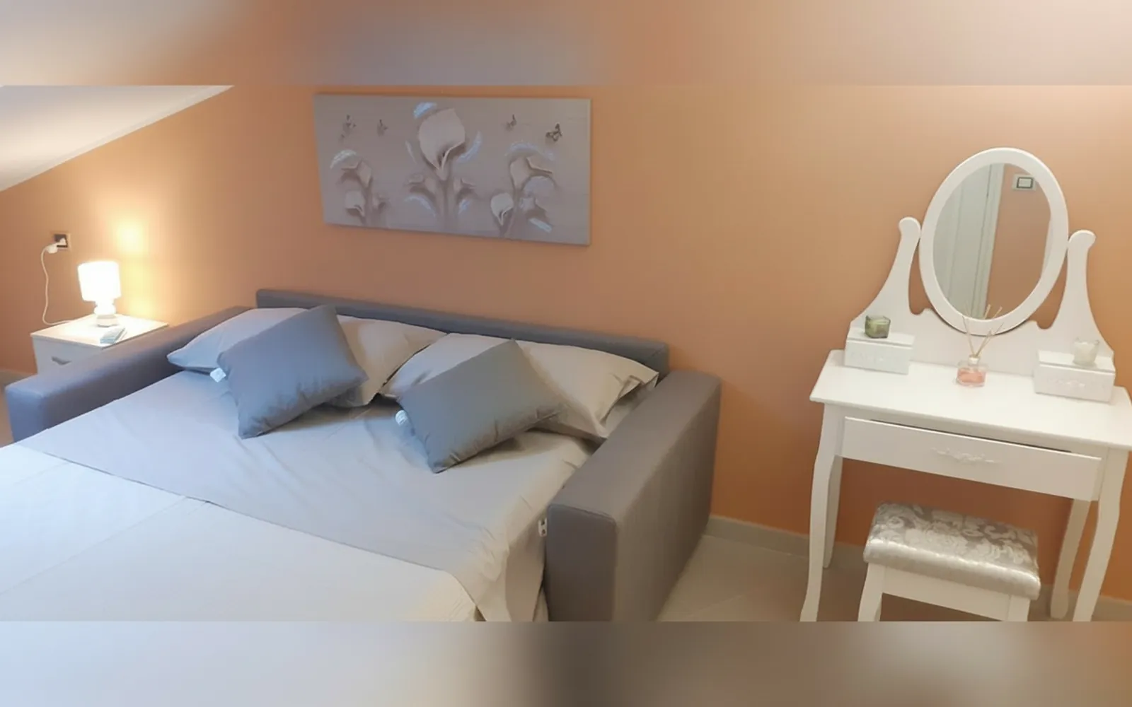 La Camera Deluxe con il letto e la toeletta bianca sotto il quadro con i fiori