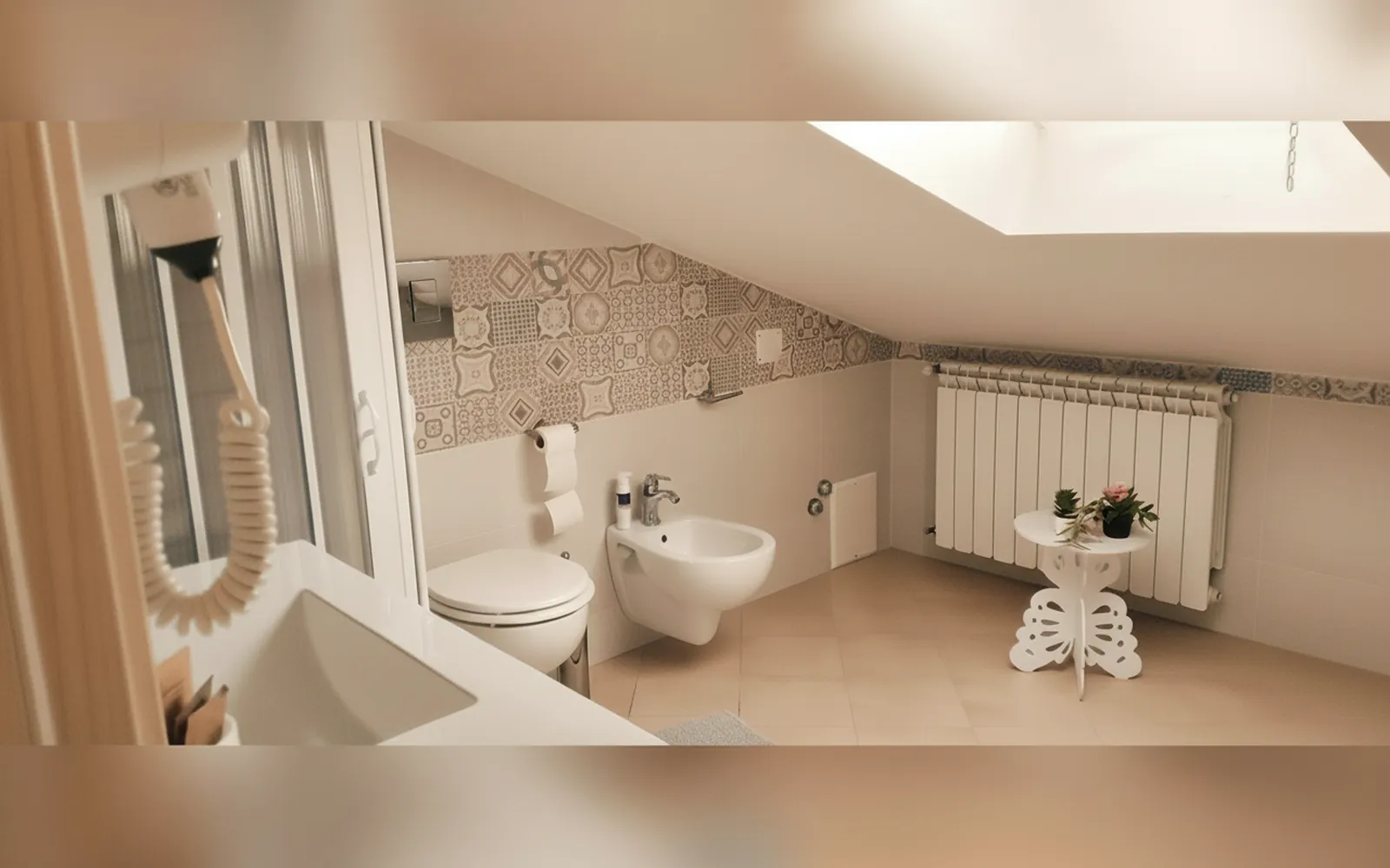 Il bagno mansardato con la doccia, i sanitari e il termosifone sotto il lucernario